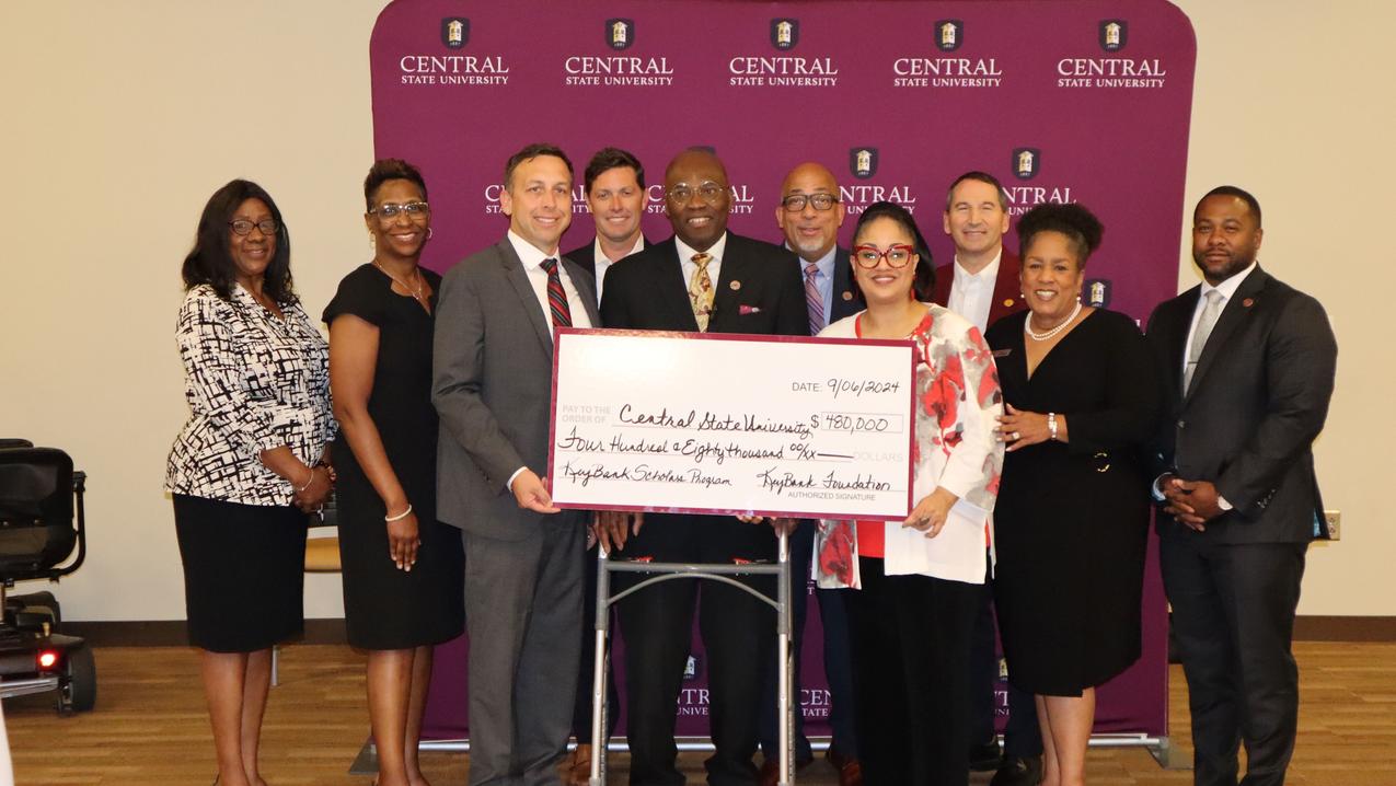 a large group of people stands in front of a central state university backdrop with president dr. morakinyo kuti and keybank representatives holding a large check