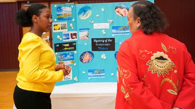Central State University student shares a posterboard with information about Bahamas with a Wilberforce community member