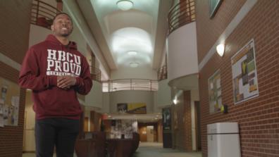 a Black male student wearing a maroon HBCU proud hoodie inside a university student center