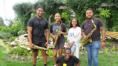 Marvin Harshaw, junior music major;  Kamille Austin, senior music major;  Corey Higgs, senior music major;  Kedron Rolle, senior music major (sitting); and Davaughn Major, 2023 music graduate, presenting jazz in the Seed-to-Bloom Botanical Garden at Central State University