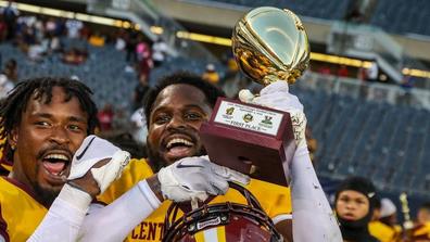 Two Marauder football players celebrate with a trophy from the Chicago Football Classic