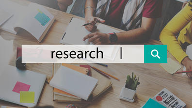 a search engine showing the word research with people working in the background