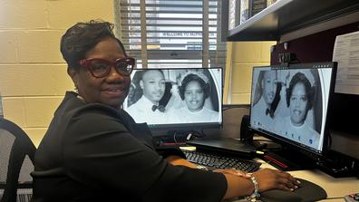 central state university college of business administrative coordinator Marchelle Jarrett-Thomas at her desk with a photo from her parents' wedding as the background on her desktop