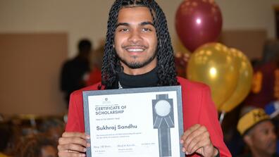 a central state university student holds a scholarship certificate at the annual alumni breakfast