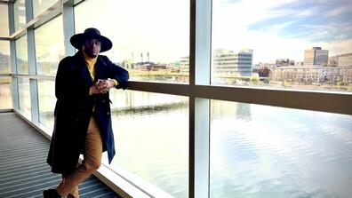 angelo hopson standing inside a building with large glass windows overlooking pittsburgh