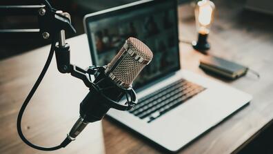 podcast microphone in front of a laptop on a desk