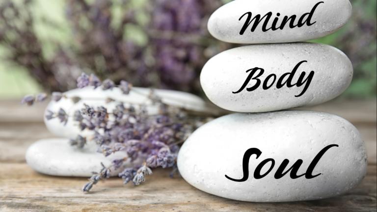 three stones in a pile with words on each stone, mind, body, and soul and lavender in the background