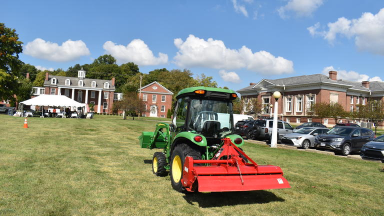 a green tractor with a red plow on the Central State University campus
