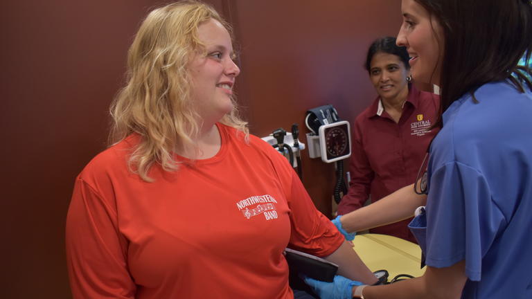 a physician assistant working with Central State University Land-Grant takes a person's blood pressure at the 2023 Farm Science Review while Dr. Anshiya Ramanitharan, health and wellness coordinator, looks on