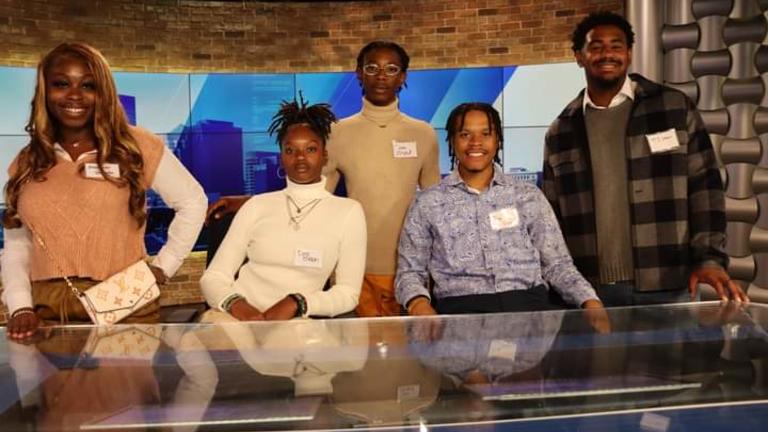 Five Well Dressed Students Sitting at New's Reporters Desk