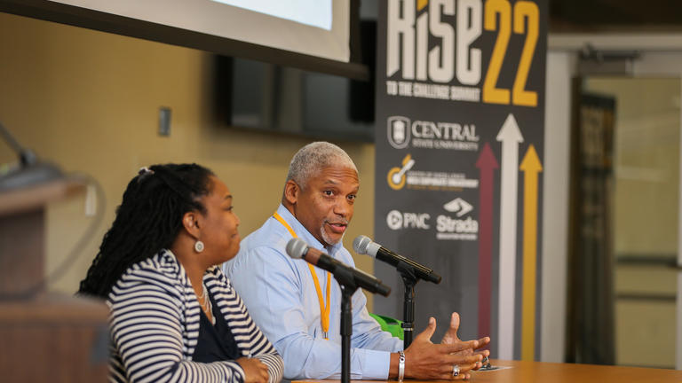two panelists sit in front of a banner for the RISE 22 RISE to the Challenge Summit in Wilberforce Ohio