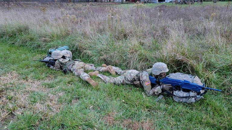 two cadets in the Battalion Ranger Challenge Team lay on the ground while practicing for the annual competition