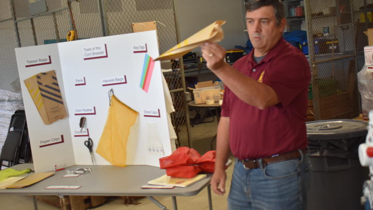 a man wearing a Central State University polo holds up a paper airplane