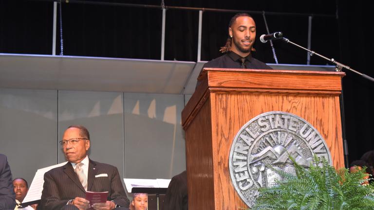 central state university student body president jordan mcmahon at podium with interim president Dr. Alex Johnson seated to his right