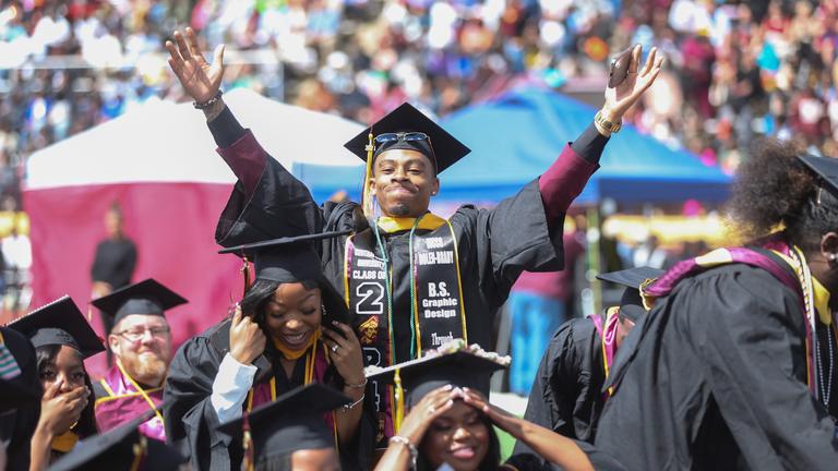 central state university graduate raises arms in celebration