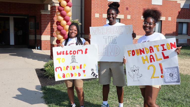 three students hold poster boards welcoming central state university students back to the wilberforce ohio campus