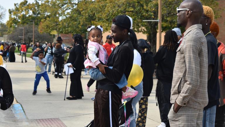 a young man holds a toddler in the crowd