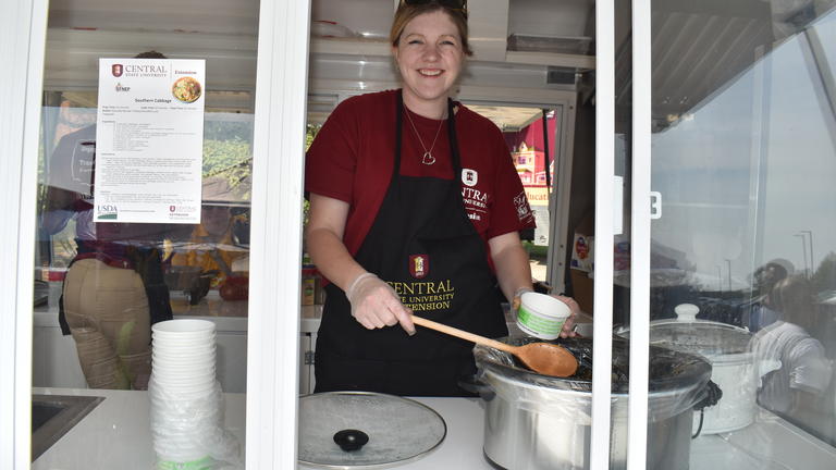 a person wearing an apron serves from a crockpot