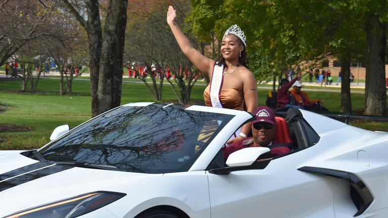 miss chase college of humanities arts social sciences and education waving from a car