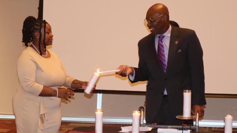 dr. kuti lighting the candle of a student government association member