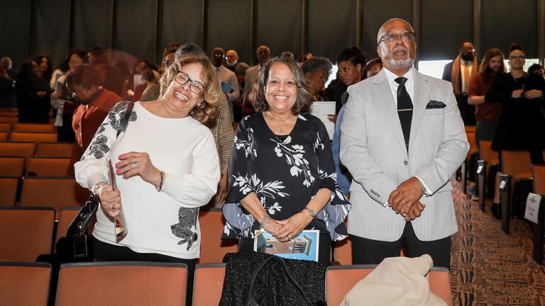 three people smile in robeson auditorium