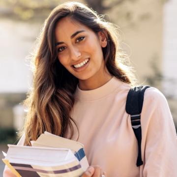 Female student standing outside holding books 