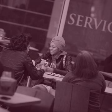 central state university students sit around a table with a sign saying service in the background