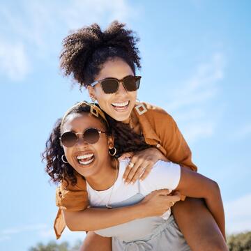 spring friends and freedom with women and piggy back against the blue sky for hug lifestyle and happy on holiday