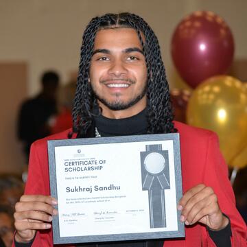 a central state university student holds a scholarship certificate at the annual alumni breakfast