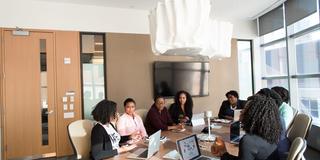 Eight professionals collaborate around a conference table in a workplace