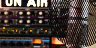 A closeup of a microphone in a radio station with the words "On Air" in all caps