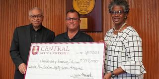 three people hold a large decorative check for University Housing Solutions' donation to Central State University in the amount of $787,000