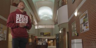 a Black male student wearing a maroon HBCU proud hoodie inside a university student center