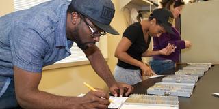 Three students work in a lab at Central State University with the student in the foreground holding a pencil