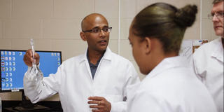 Dr Kumaran holding a beaker while giving a lab demonstration