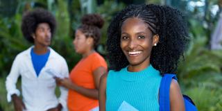 African American woman holding folder with backpack and two other Black students in the background