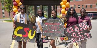 five Central State University students hold signs welcoming the class of 2027 to campus