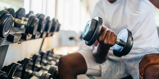 an African American man lifts weights in a fitness center
