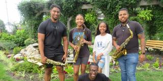 Marvin Harshaw, junior music major;  Kamille Austin, senior music major;  Corey Higgs, senior music major;  Kedron Rolle, senior music major (sitting); and Davaughn Major, 2023 music graduate, presenting jazz in the Seed-to-Bloom Botanical Garden at Central State University