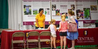 A representative of Central State University Land-Grant talks with youth at the 168th Ohio State Fair