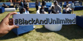 An African American holds a sign with the hashtag Black and Unlimited as part of Walmart's tour of HBCUs