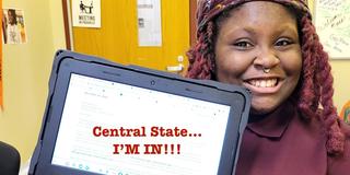a young african american person with braids and a nose ring holds a laptop with the words central state... I'm in celebrating her acceptance to central state university