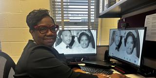 central state university college of business administrative coordinator Marchelle Jarrett-Thomas at her desk with a photo from her parents' wedding as the background on her desktop