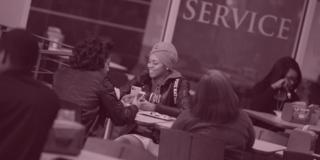 central state university students sit around a table with a sign saying service in the background