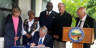 ohio governor mike dewine signs a bill while five others look on