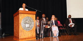 speaker latoya turner speaks at a podium with leadership looking on nearby at a freshman convocation in the paul robeson cultural and performing arts center