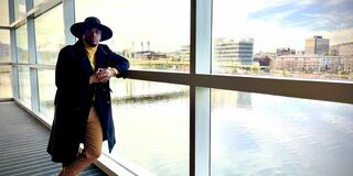 angelo hopson standing inside a building with large glass windows overlooking pittsburgh