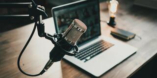 podcast microphone in front of a laptop on a desk