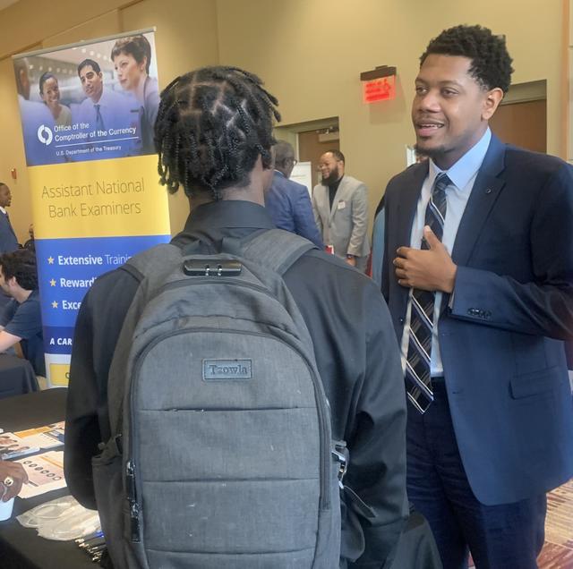 Devin Watkins, a 2018 graduate of Central State University and  Associate National Bank Examiner for the U.S. Department of Treasury, Office of the Comptroller of Currency, speaks with a student at the annual career fair.