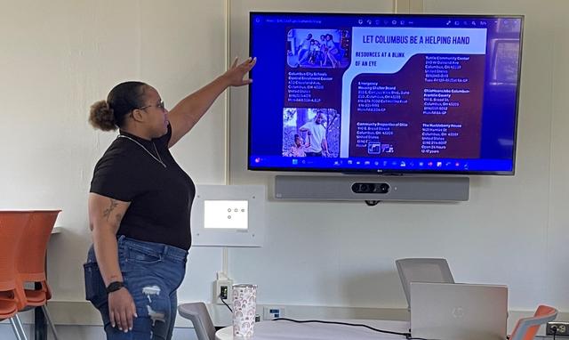 An Honors student points to a TV display with Columbus, Ohio, resources